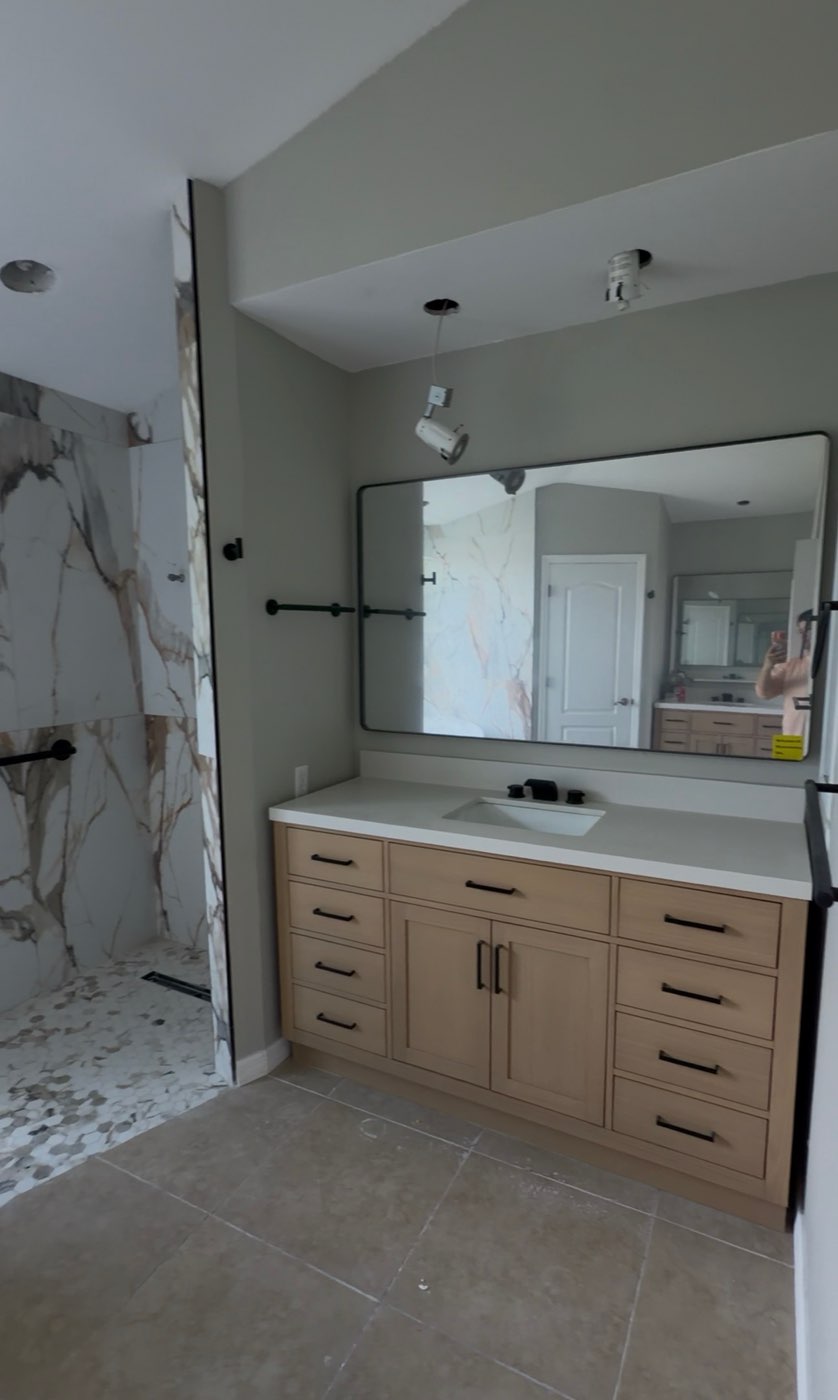 Bathroom vanity with framed mirror and marble tile
